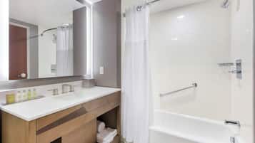 A modern bathroom with a double sink vanity, a shower with a glass door, and a large mirror.