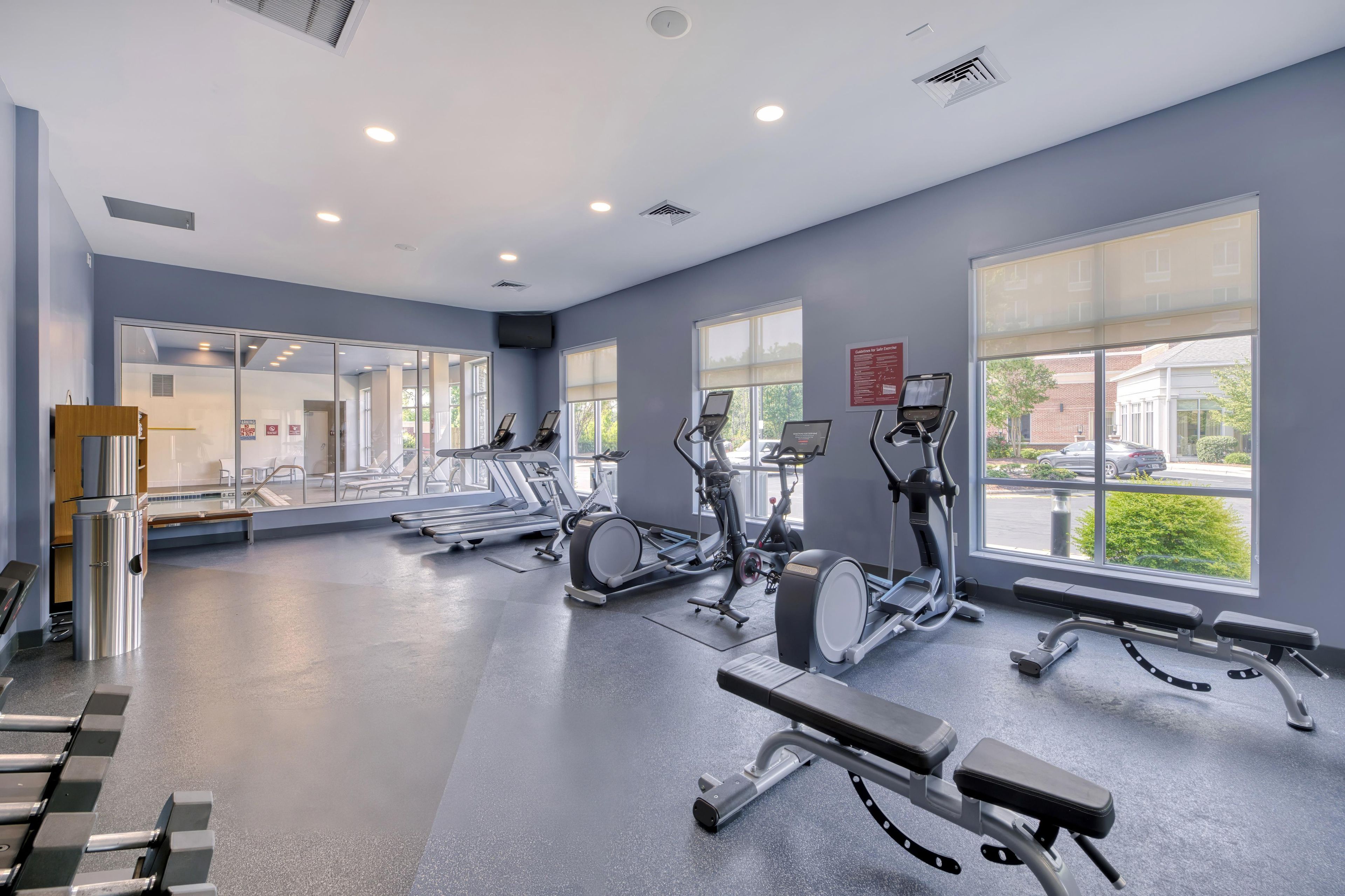 A gym with various exercise equipment, large windows, and a clean, modern design.
