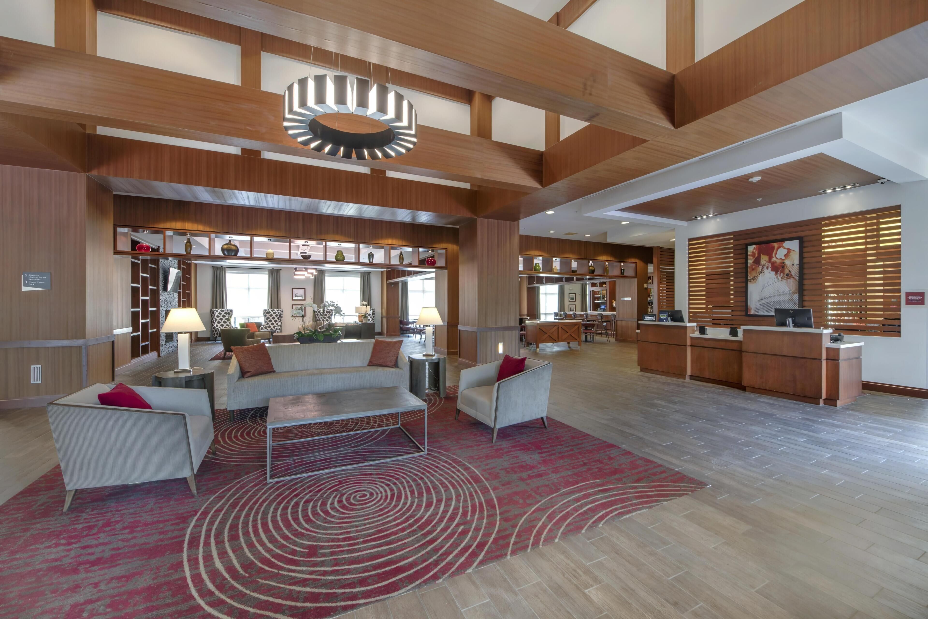 A spacious lobby with a reception desk, seating area, and a patterned rug.