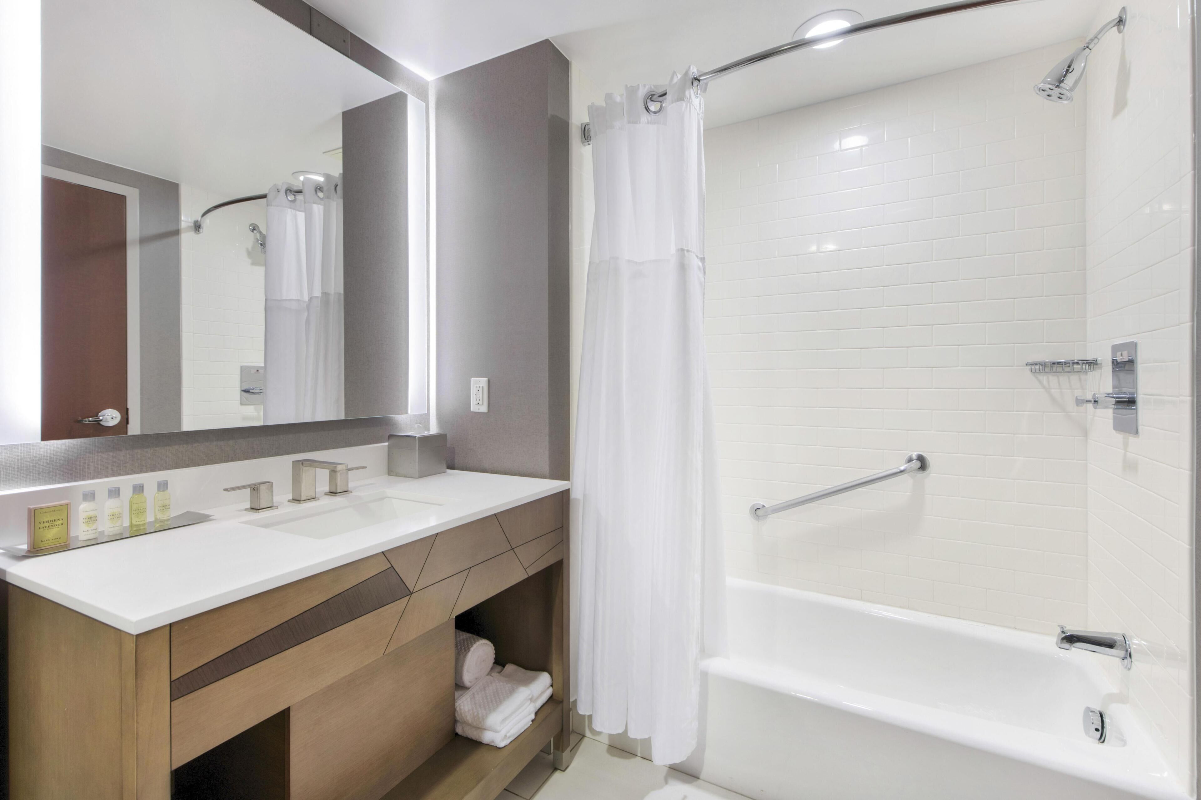 A modern bathroom with a shower, a sink, and a mirror.