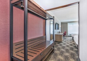Habitación de hotel con cama, escritorio, silla y un espejo grande.