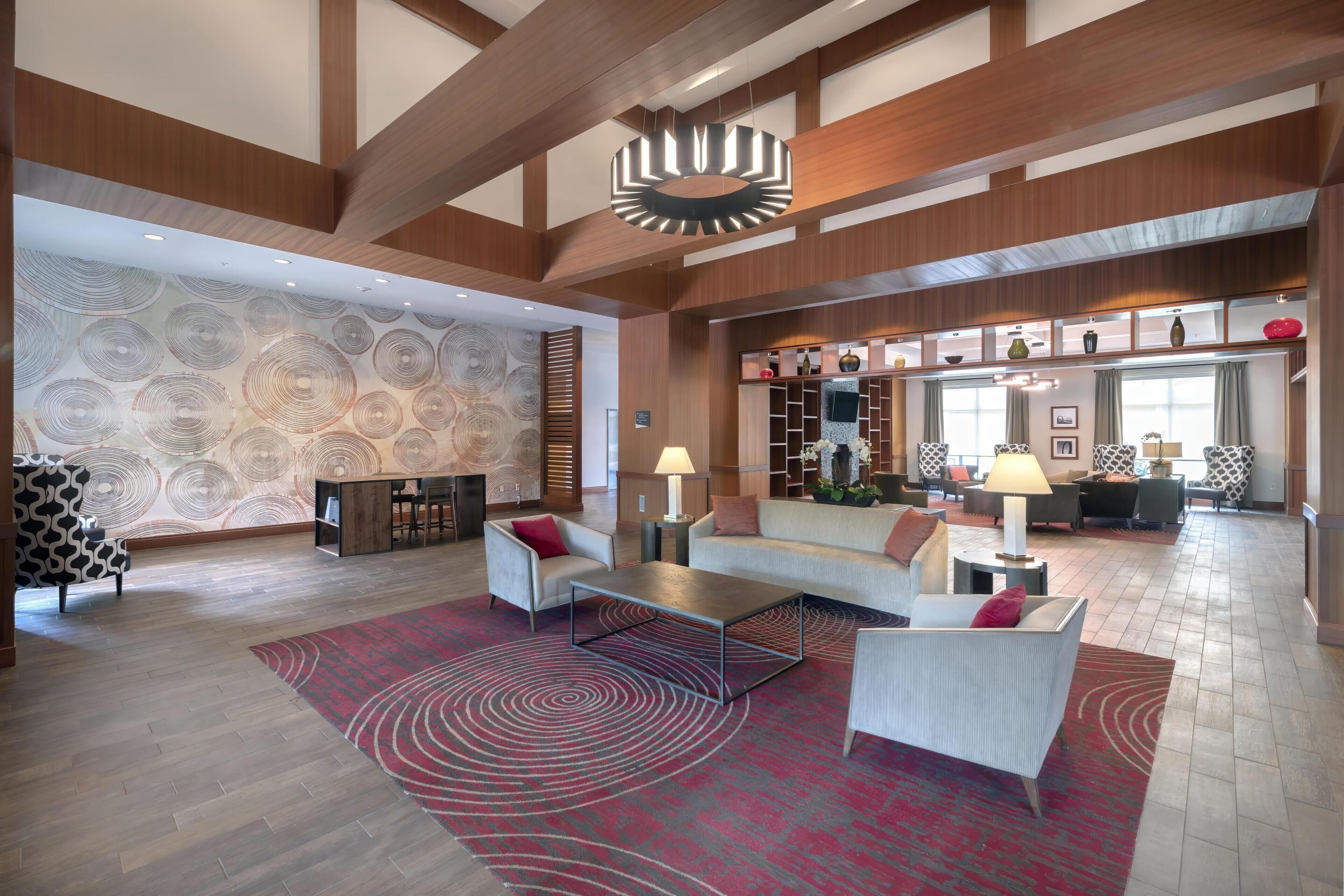 Um hall amplo com design moderno, com uma grande área de estar, parede estampada e luminária decorativa no teto.