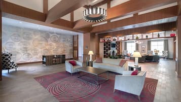 Um hall amplo com design moderno, com uma grande área de estar, parede estampada e luminária decorativa no teto.
