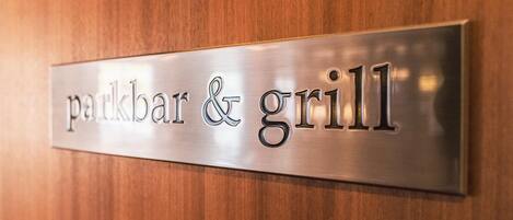 Placa metálica com a inscrição 'parkbar & grill', indicando um restaurante.