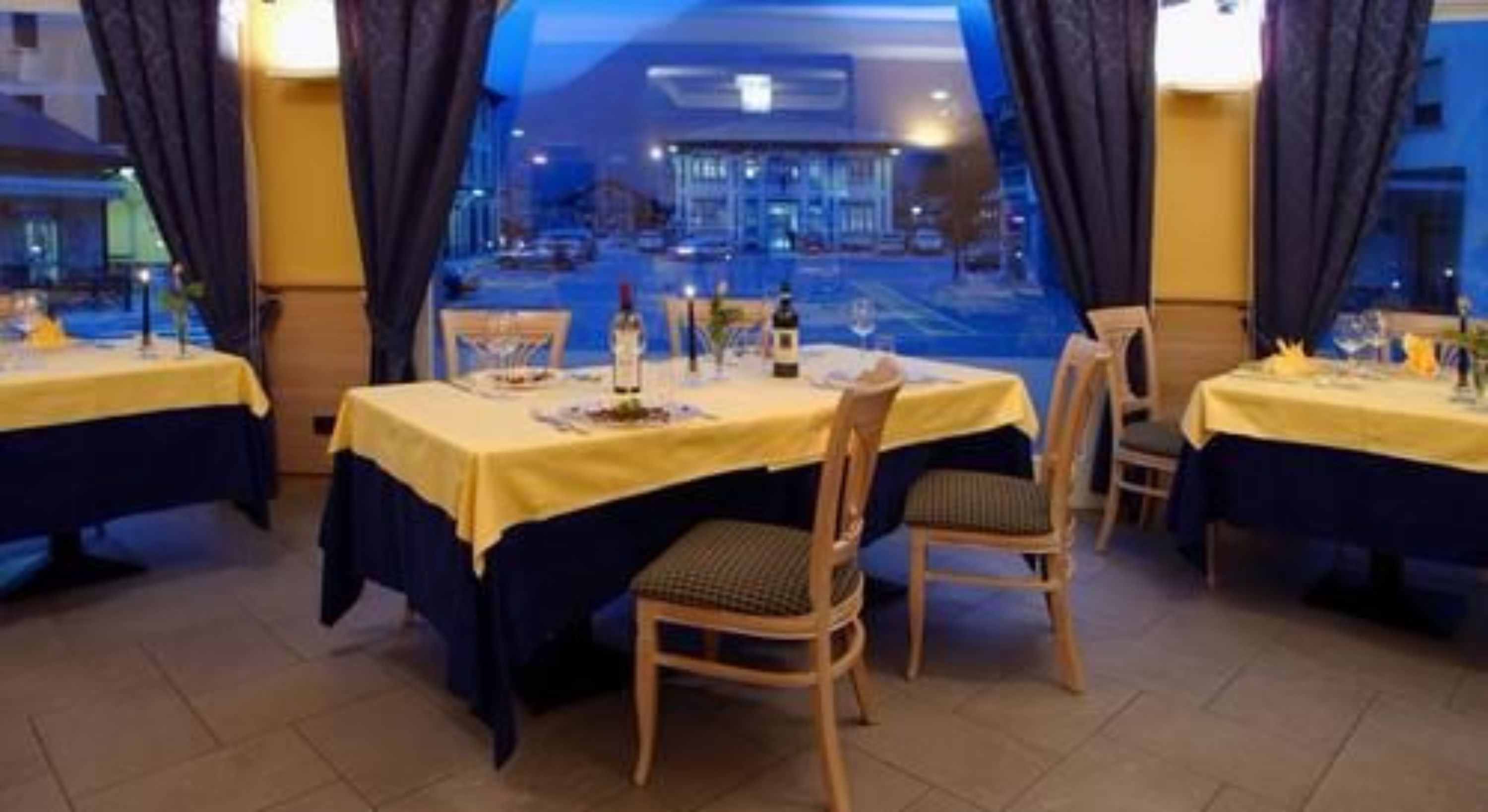 Un restaurante con mesas dispuestas para comer, sillas y vistas a la calle.