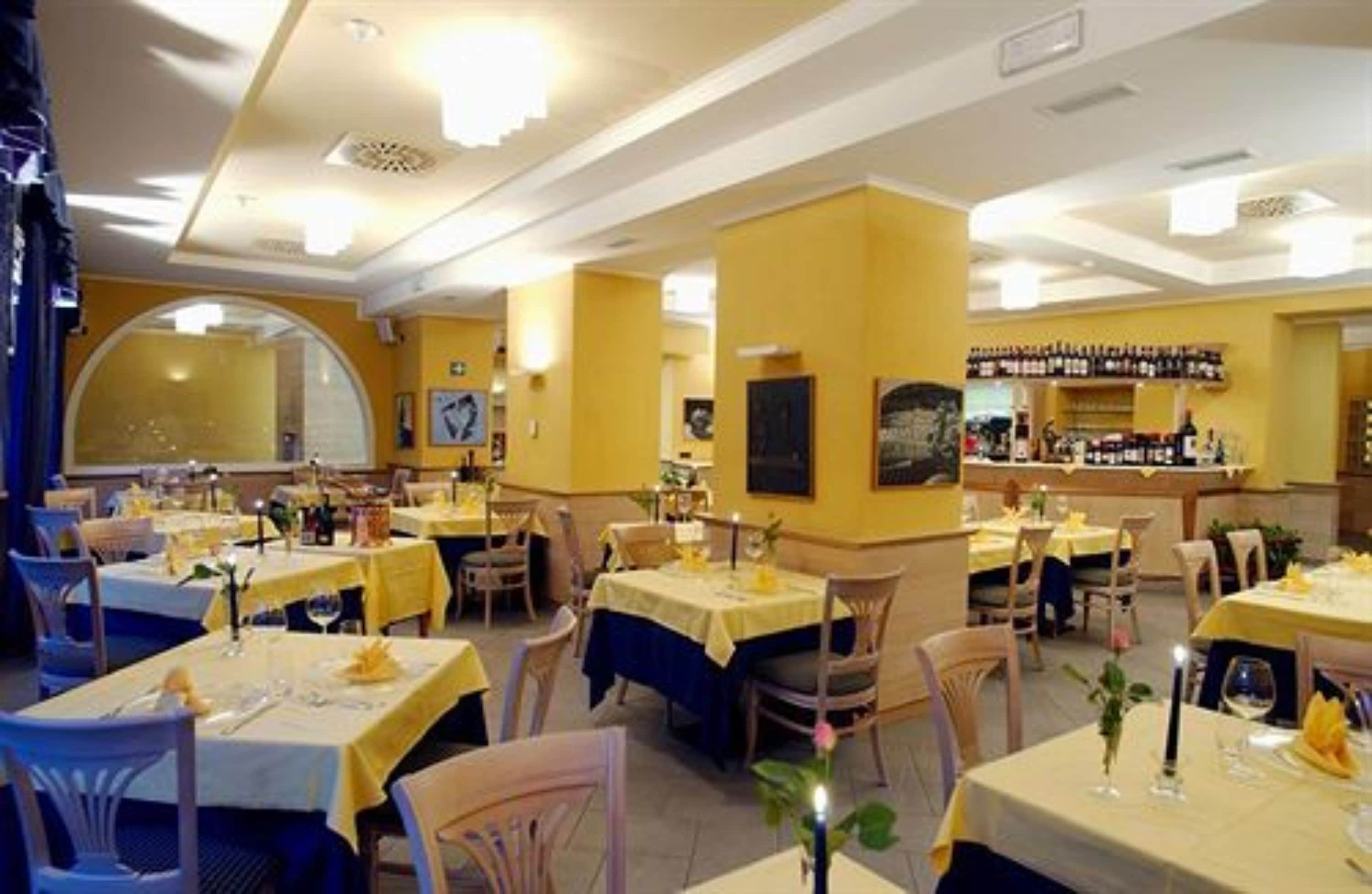 Ein Restaurant mit gelben Wänden, runden Tischen und einer Bar.