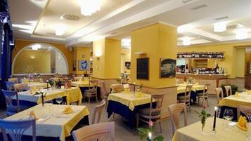 Ein Restaurant mit gelben Wänden, runden Tischen und einer Bar.