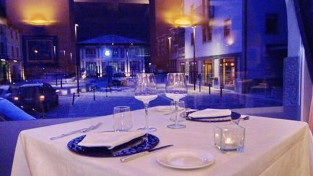 A table set for dining with a view of a cityscape at night. - Hotel Bernina (Tirano)