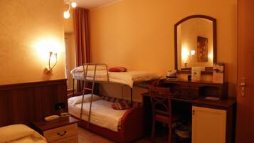 Une chambre d’hôtel compacte comprenant un lit superposé, un bureau avec une chaise, un petit placard et un miroir.