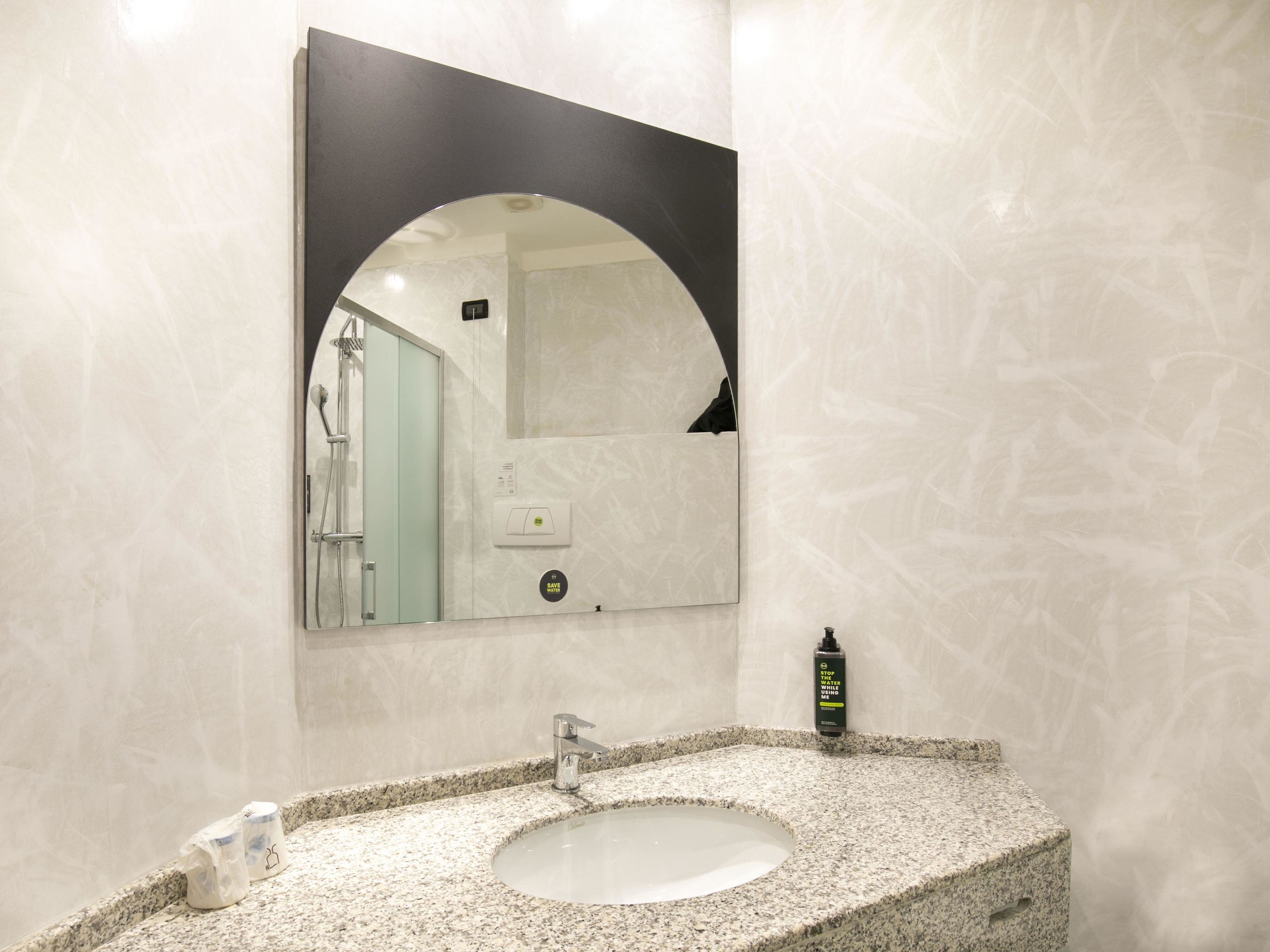 Un bagno con un lavabo in granito, uno specchio e una doccia visibile nel riflesso.