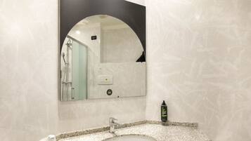 Un bagno con un lavabo in granito, uno specchio e una doccia visibile nel riflesso.