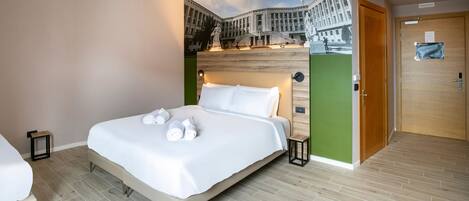 A modern hotel room with a large bed, a small bedside table, and a wall mural.