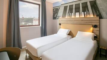 A hotel room with two single beds, a large window, and a view of the cityscape.