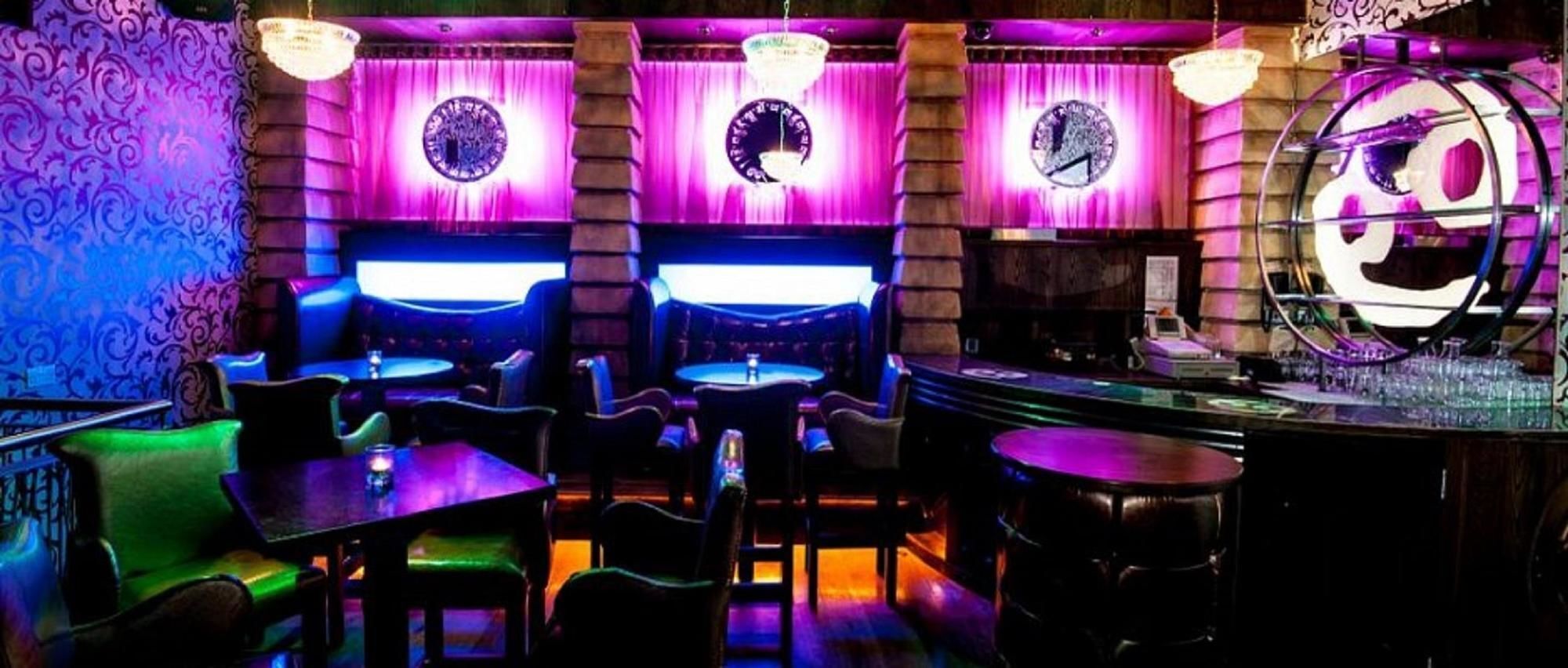 A bar area with multiple seating arrangements, including tables and chairs, and a bar counter.