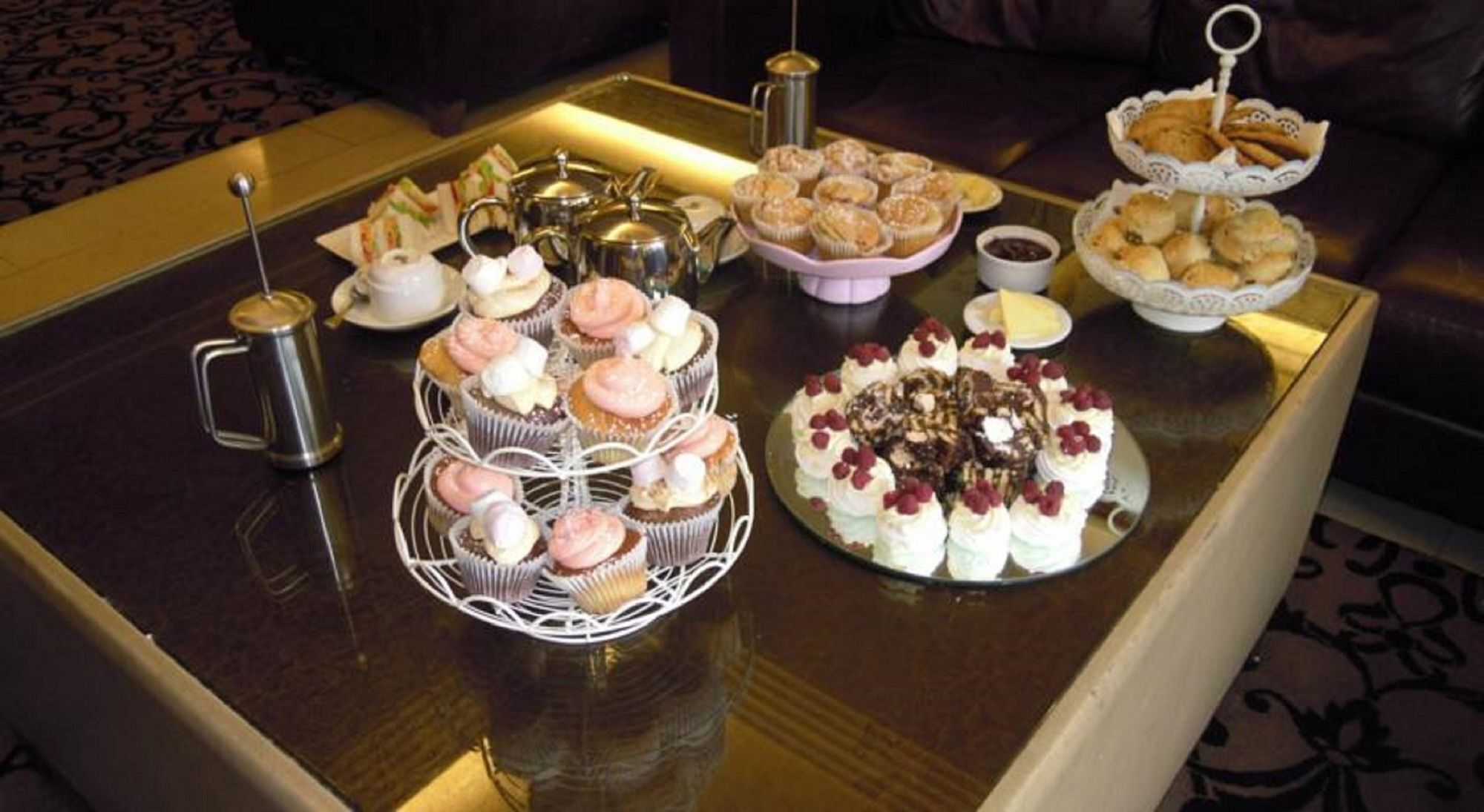 A table with various pastries and a teapot.