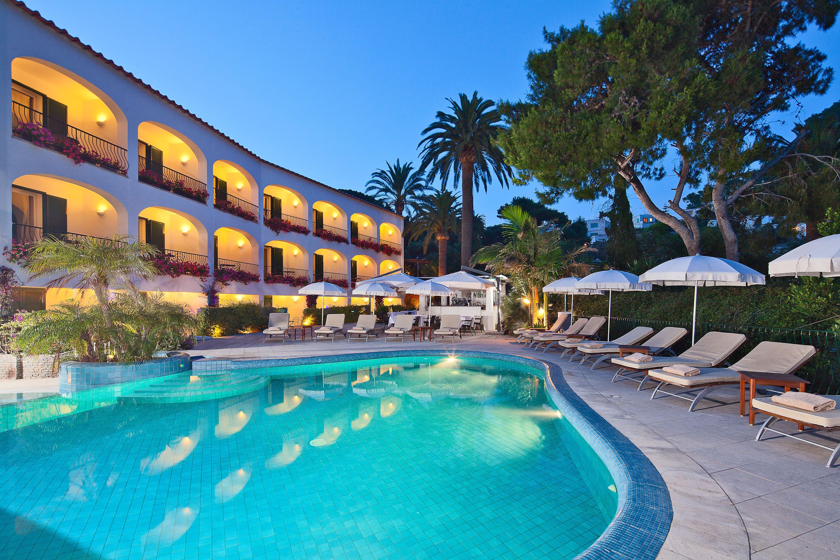 Ein Hotel mit Schwimmbad, Liegestühlen und Sonnenschirmen.