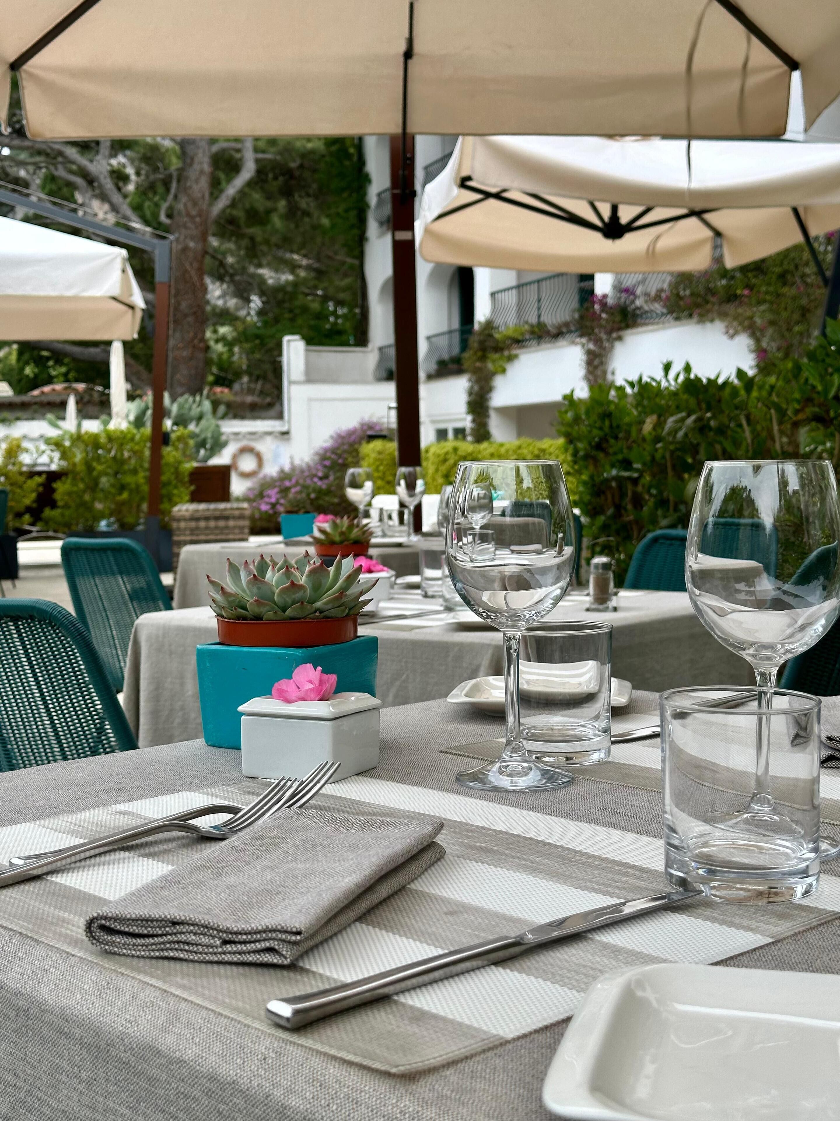 Mesa lista para comer al aire libre, con vista a un edificio y follaje en el fondo.
