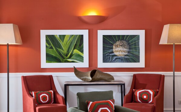 A room with two red armchairs, a green sofa, a small table, and two wall-mounted lamps. There are two framed pictures on the wall. - Hotel della Piccola Marina (Capri)