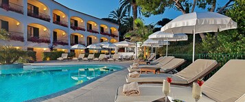 Una piscina al aire libre, sombrillas, sillones reclinables de piscina