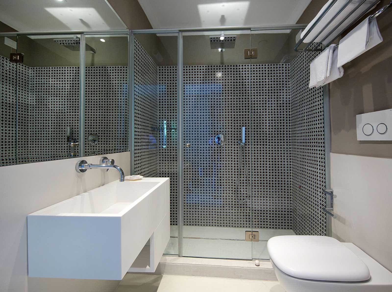 A modern bathroom with a glass-enclosed shower, a white sink, and a toilet.