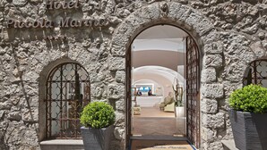 Fachada de piedra con aberturas en arco y una recepción visible a través de la entrada.