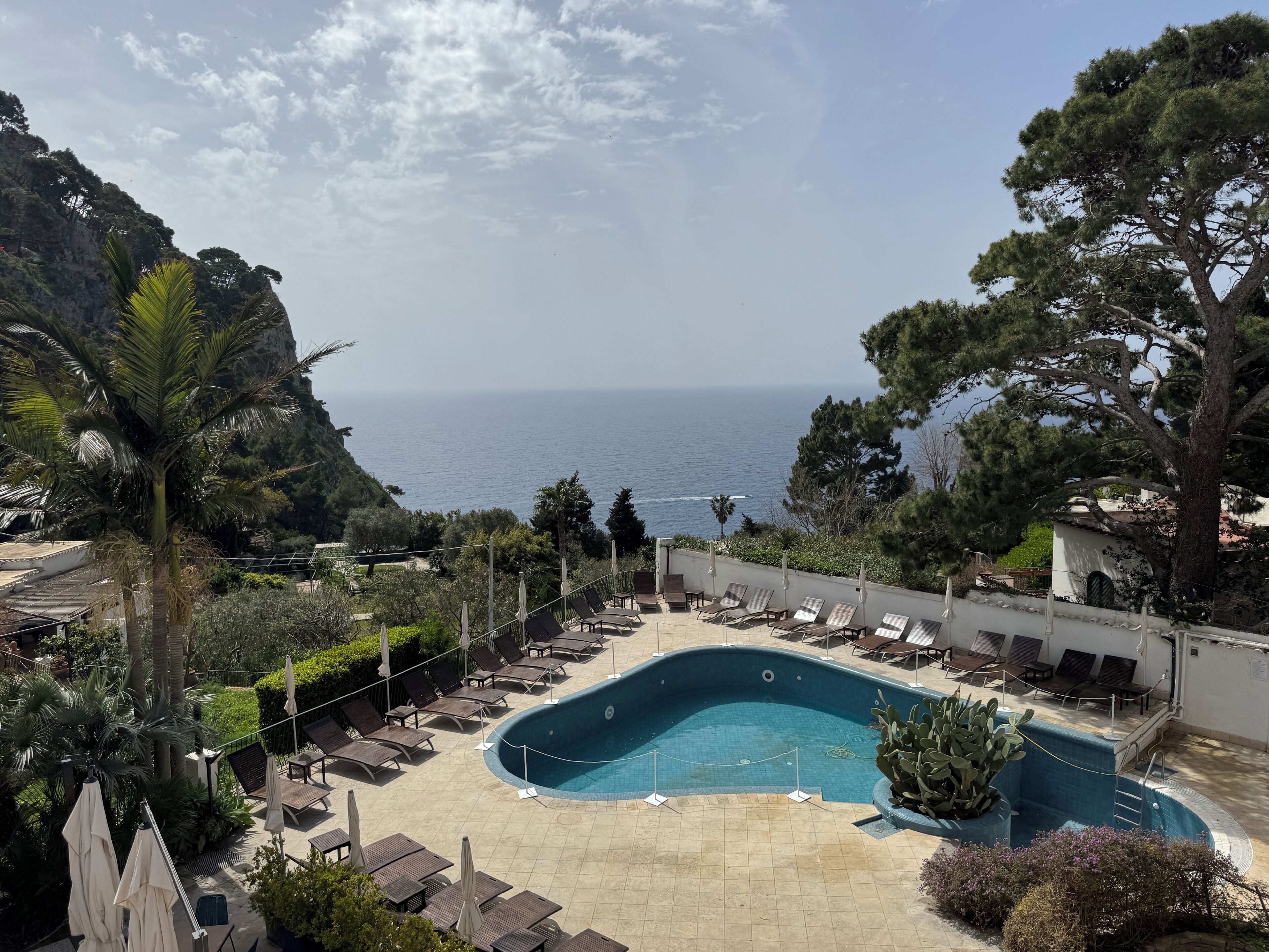 A pool area with lounge chairs and a view of the sea.