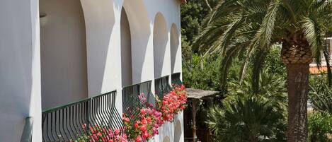 A building with white walls and green balconies, surrounded by palm trees.
