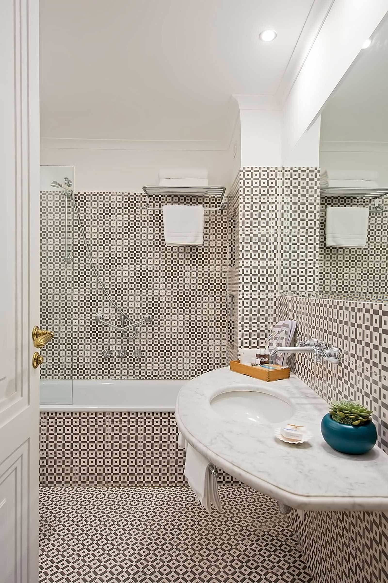 Une salle de bain avec des murs recouverts de carreaux à motifs, un lavabo en marbre et un espace douche.