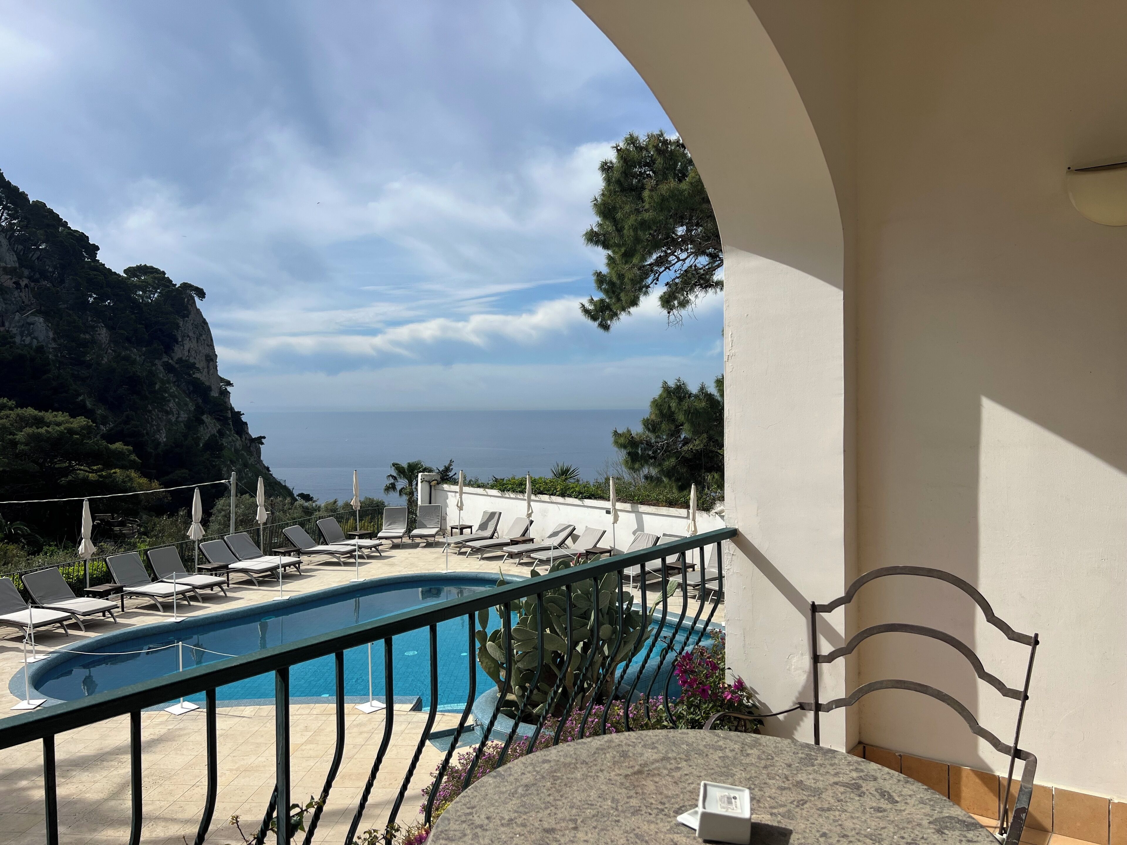 A pool area with lounge chairs and a view of the sea.