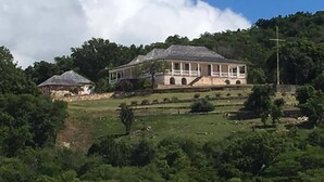 A large, two-story building with a covered porch and a staircase leading to the upper level. - HBK Villa Rentals at Jolly Harbour (Jolly Harbour)