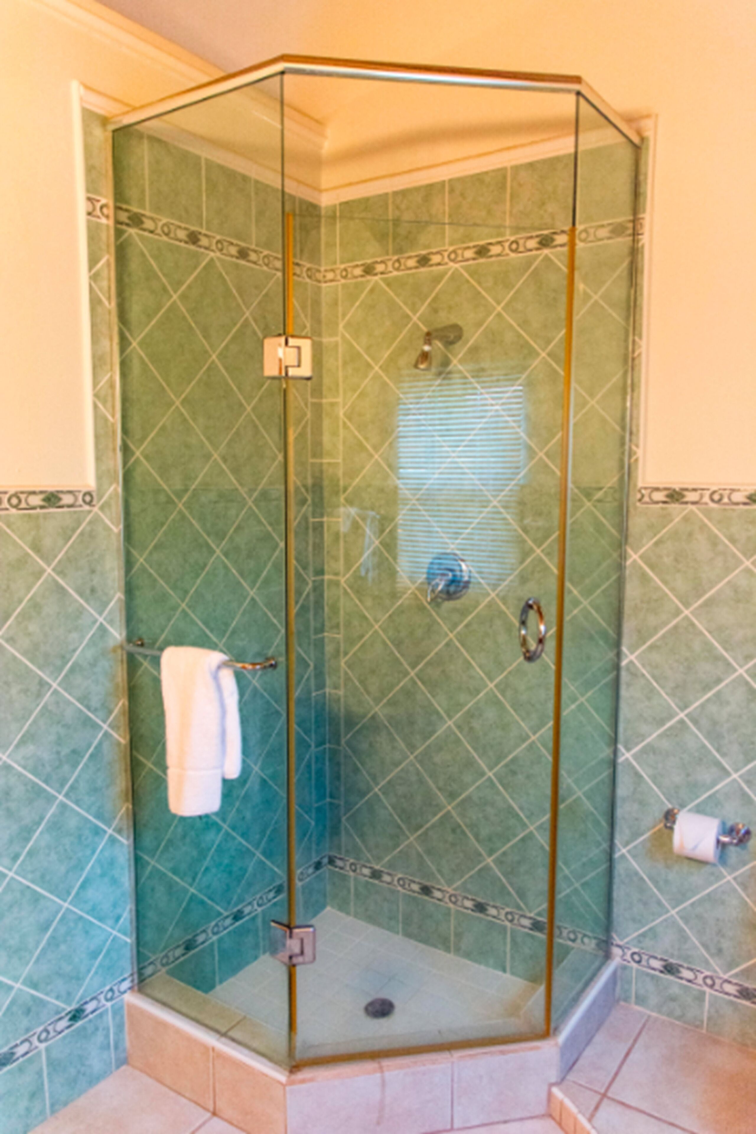 Ducha con paredes de cristal y una toalla blanca colgada del pomo de la puerta.