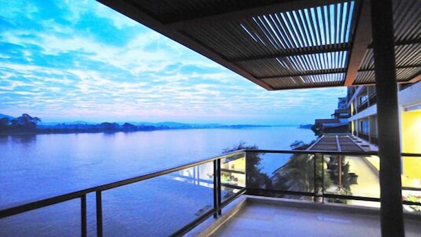 A balcony with a view of a calm river and distant mountains under a clear sky. - Serene at Chiang Rai (Chiang Saen)