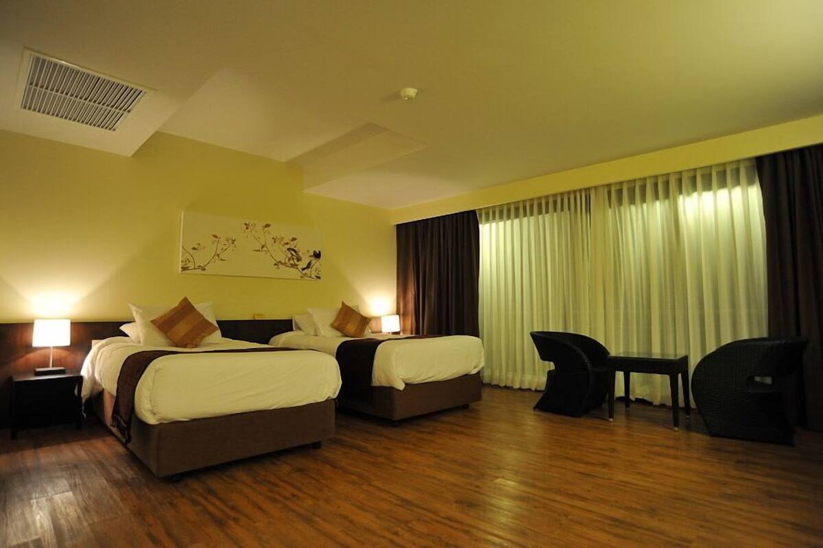 A hotel room with two beds, a desk, and a chair.