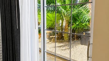 Een glazen schuifdeur die leidt naar een terras met tegels en plantenpotten.