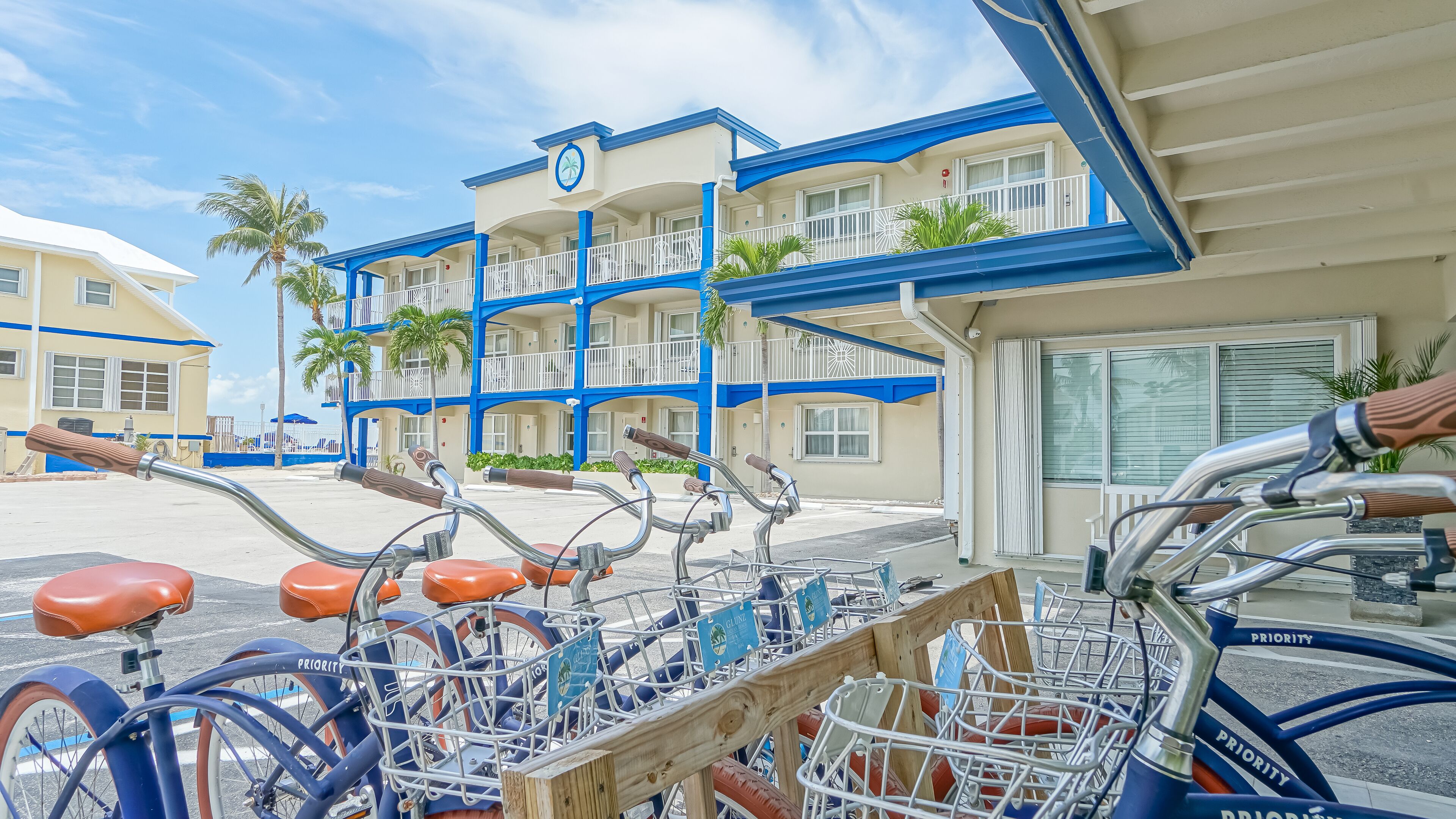 A hotel with multiple floors, balconies, and a parking area with bicycles.