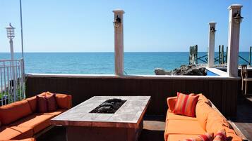 A terrace with orange seating and a fire pit, overlooking the sea.