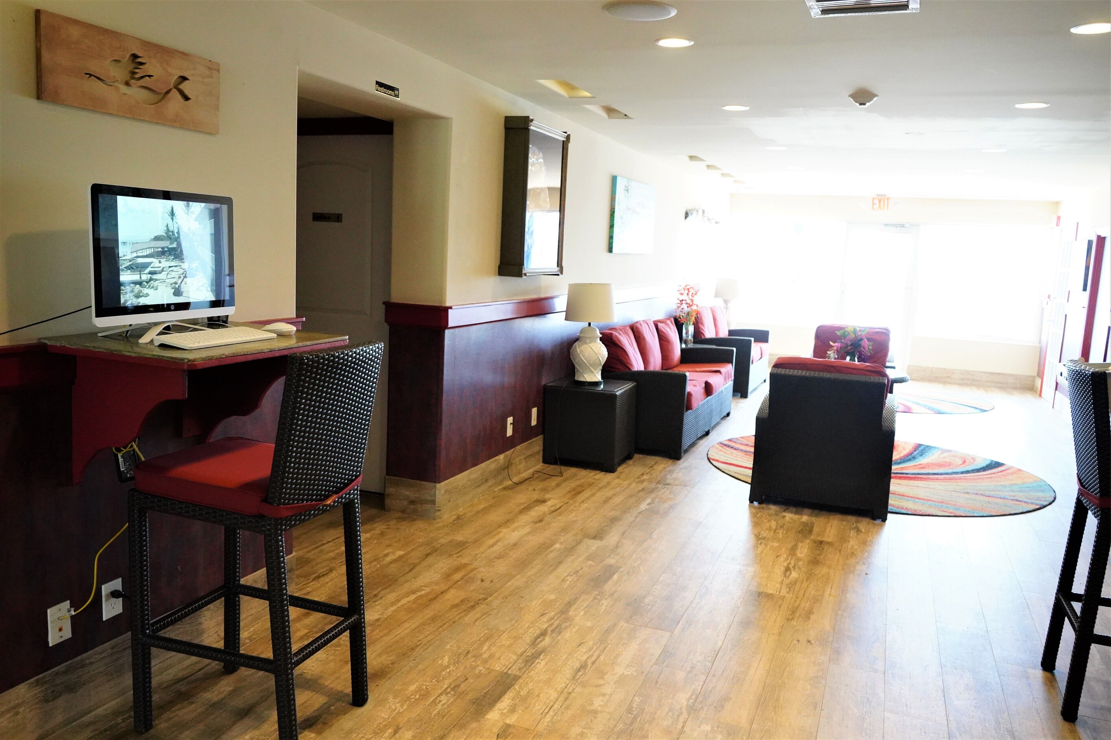 A hotel lobby with a reception desk, seating area, and a wooden floor.