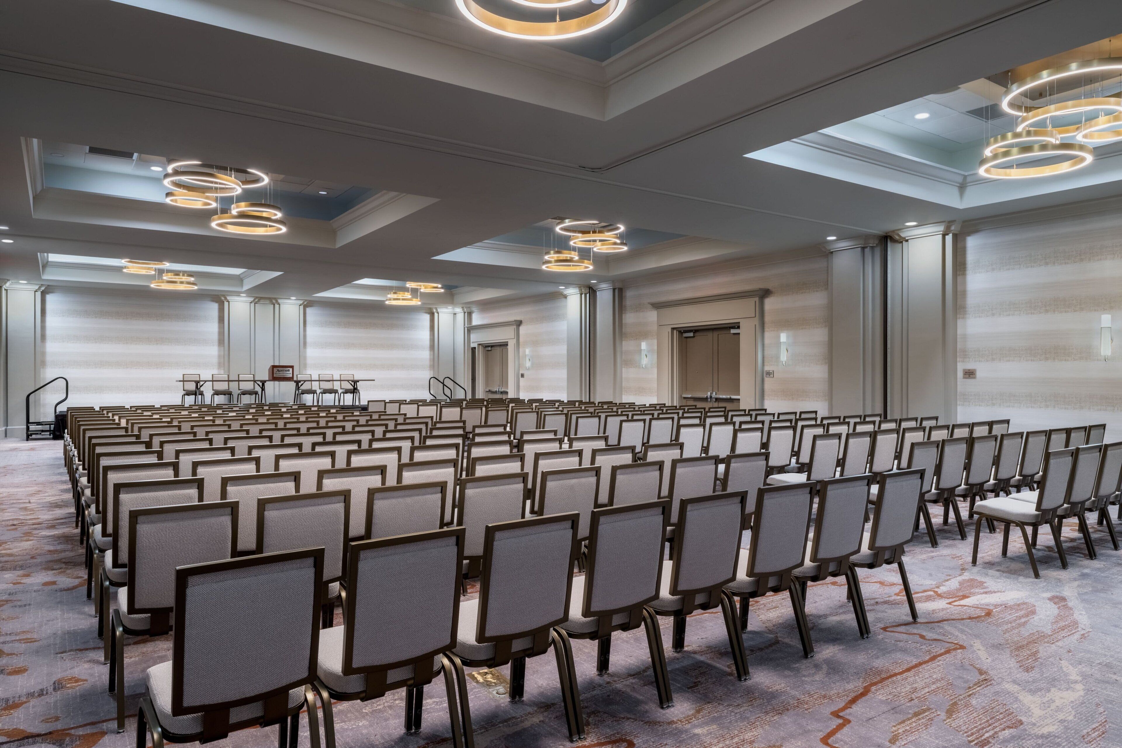 A conference room with rows of chairs, a stage, and modern lighting fixtures.
