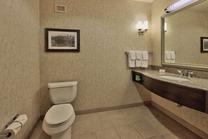 Une salle de bain comprenant des toilettes, un lavabo, un miroir et un tableau encadré accroché au mur.