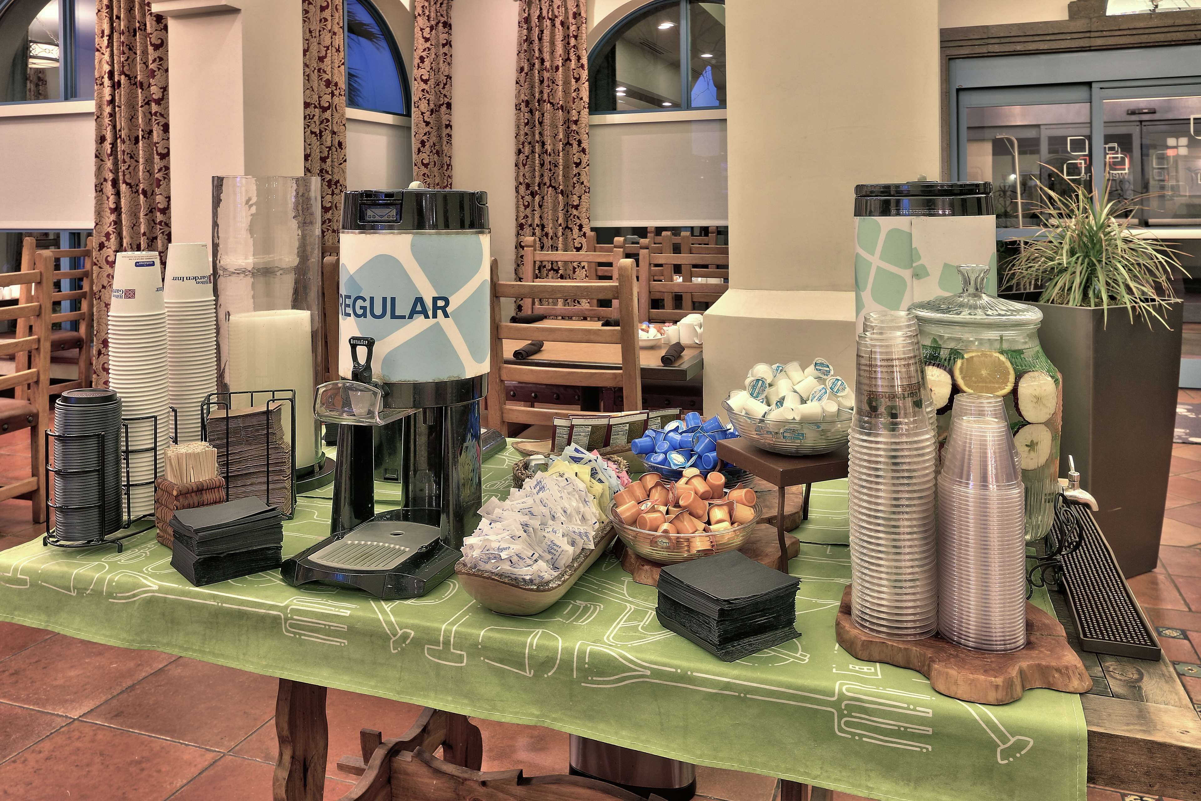 A buffet table with various food items and utensils, including stacks of plates, bowls, and condiment containers.