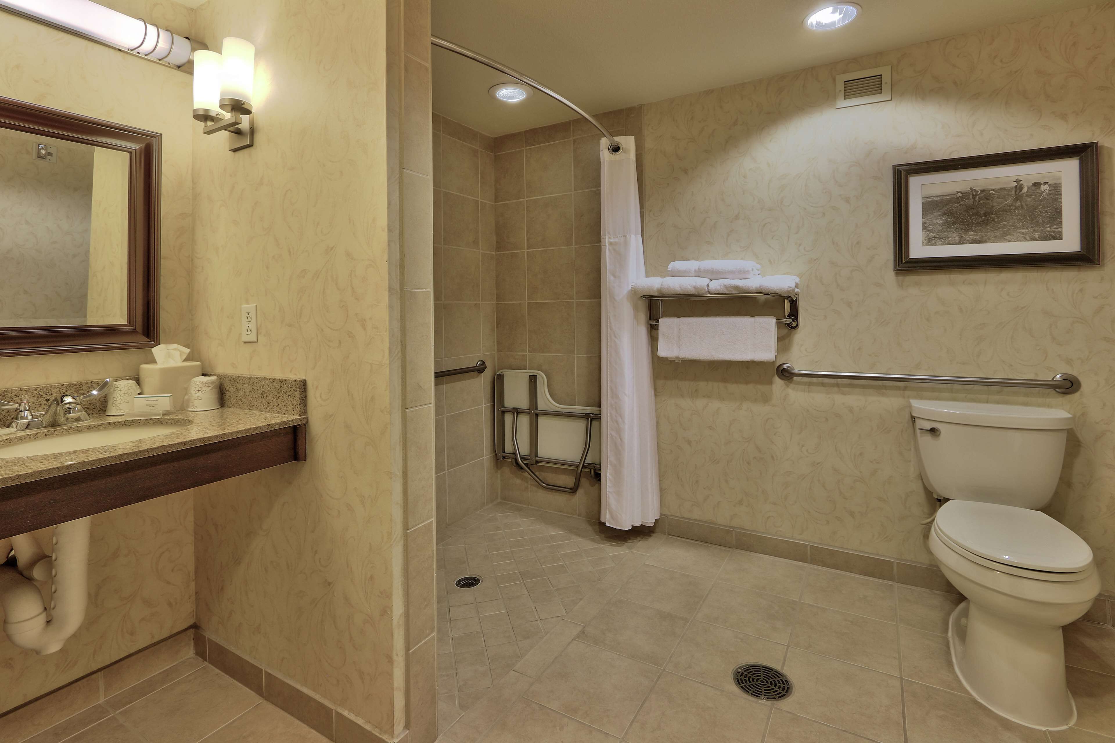 A bathroom with a sink, mirror, toilet, shower, and a towel rack.