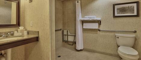 A bathroom with a sink, mirror, toilet, shower, and a towel rack.