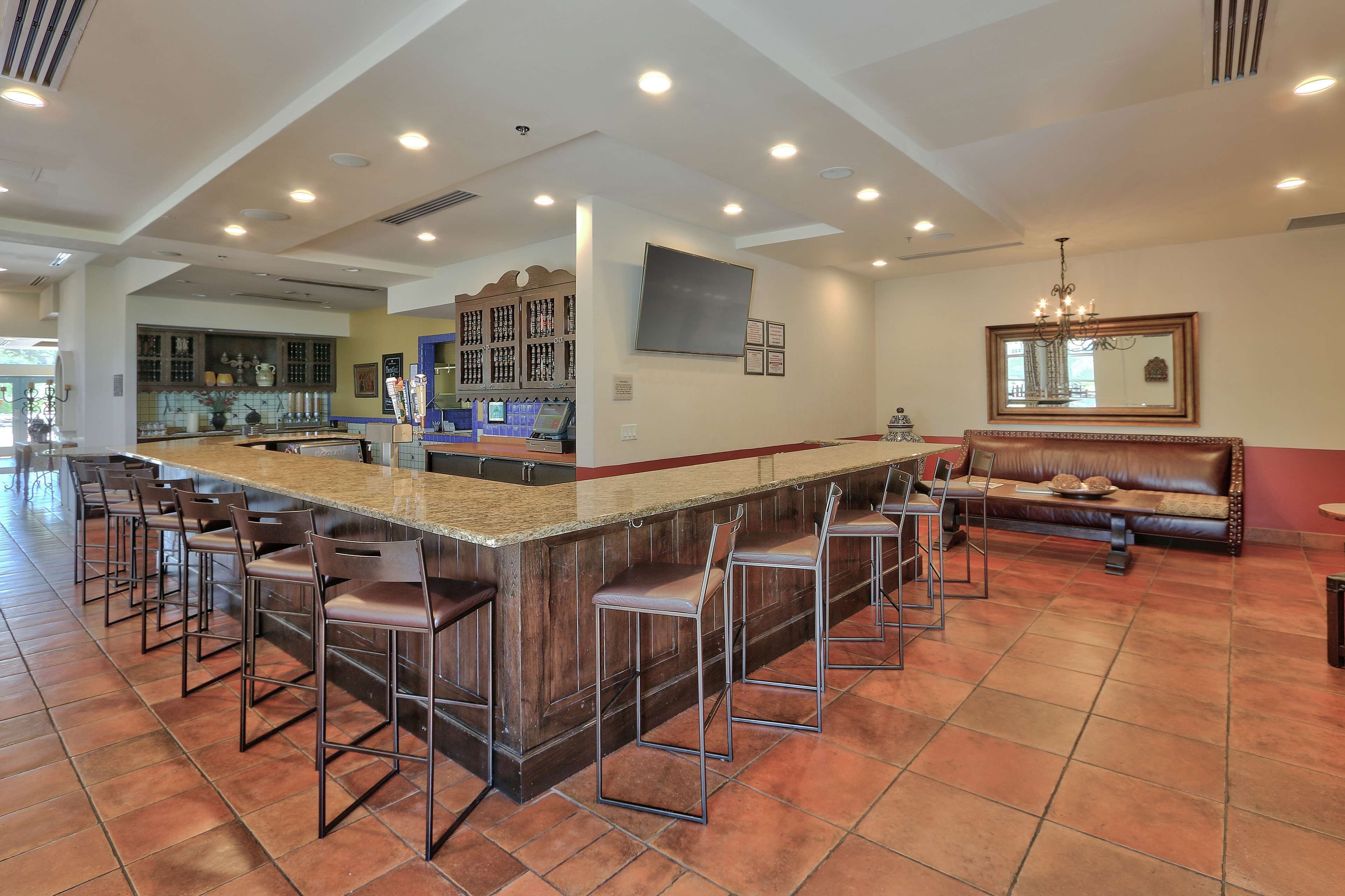 A spacious kitchen with a central island, bar stools, and a seating area with a sofa and chairs.