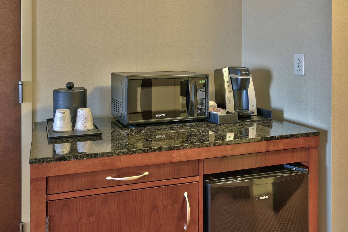 A kitchen area with a microwave, coffee maker, and a dishwasher.