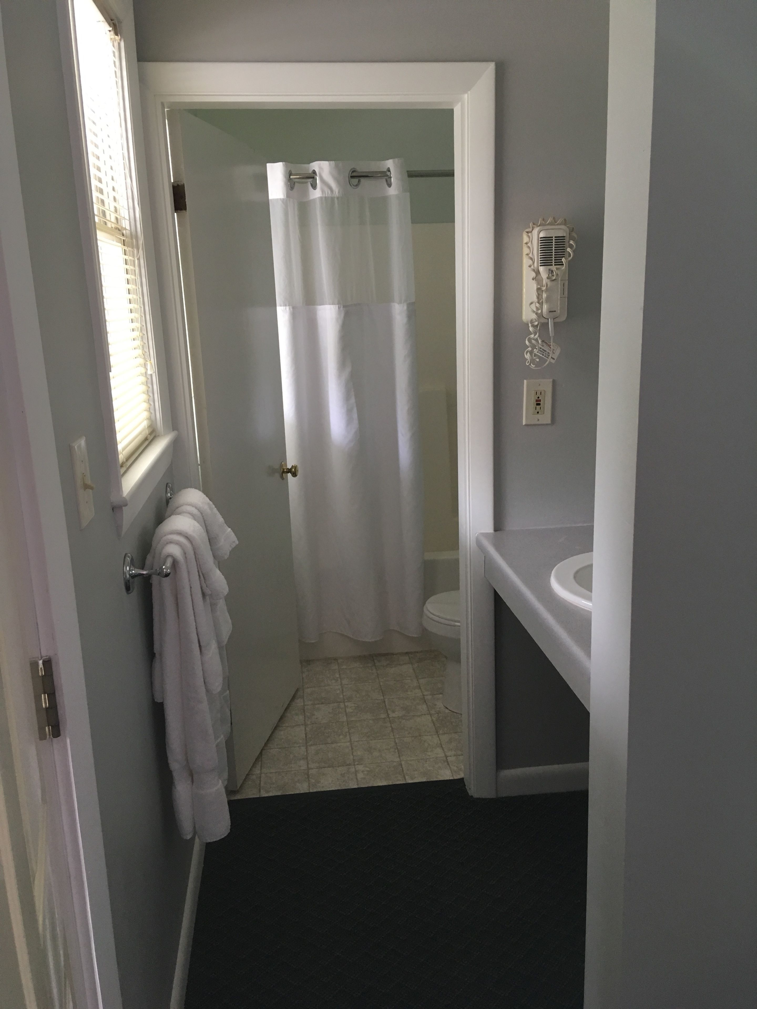 A bathroom with a toilet, a sink, a shower curtain, and a towel rack.