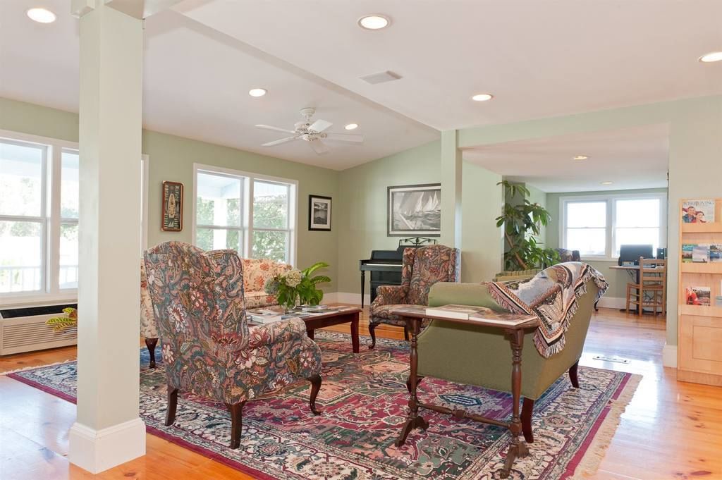 A spacious living room with a large window, a ceiling fan, and a piano.
