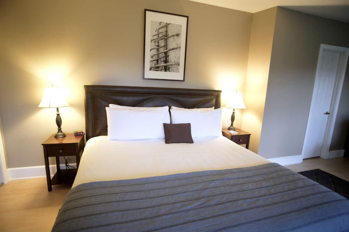 A neatly made bed with a dark headboard, two bedside tables with lamps, and a framed picture on the wall.