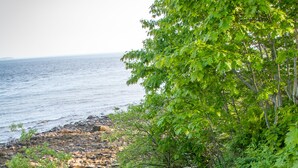 A wooden staircase leading to a rocky shoreline with a view of the ocean. - Glenmoor By the Sea (Lincolnville)