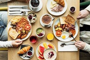 A breakfast setting with various dishes including toast, eggs, sausages, and a croissant.