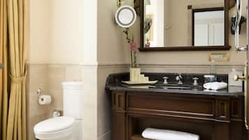 Un baño con inodoro, lavamanos, espejo y toallero.
